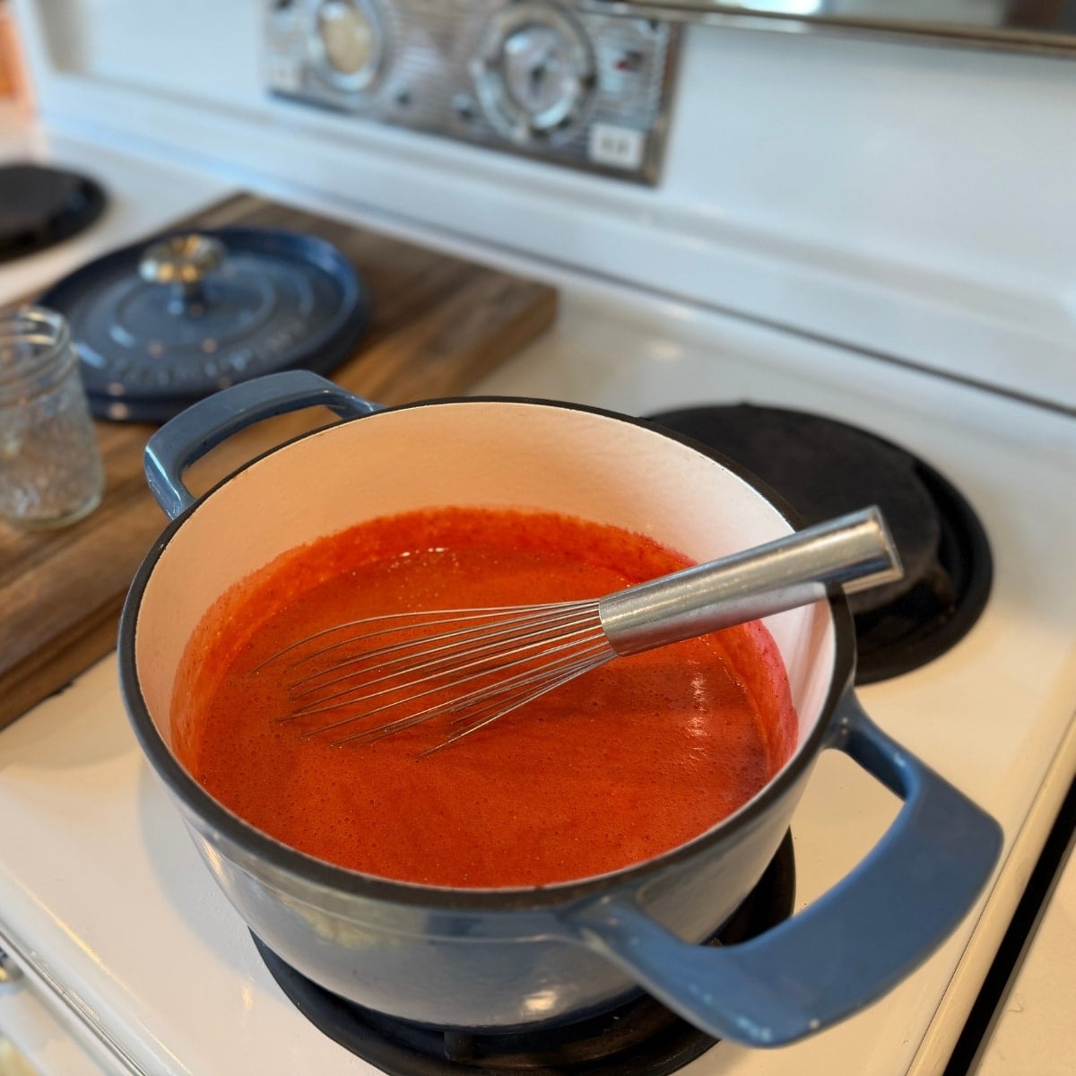 strawberry puree with calcuim water heating on stove - bringing to a boil before adding sweetener with pectin