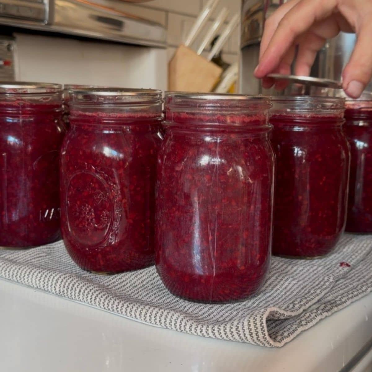 adding lids to hot jars of honey blackberry jam