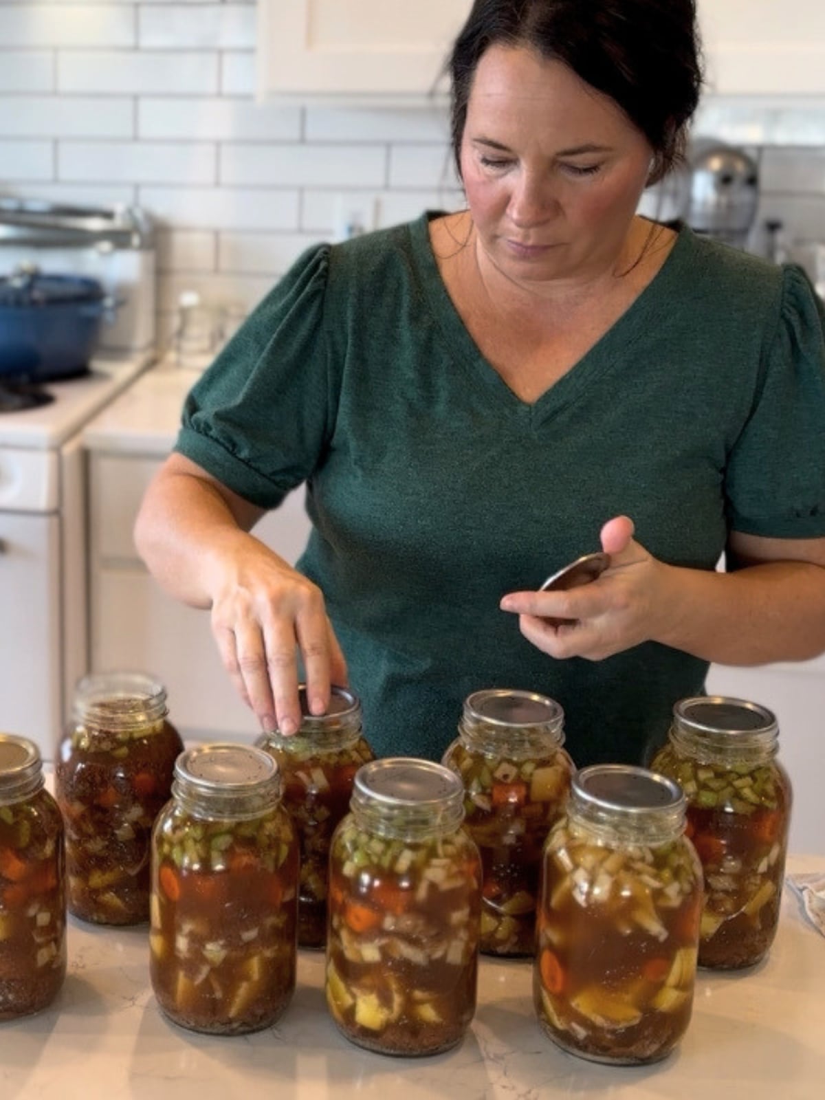 juliea from farmhouse harvest putting lids on jars of raw packed beef stew canning recipe