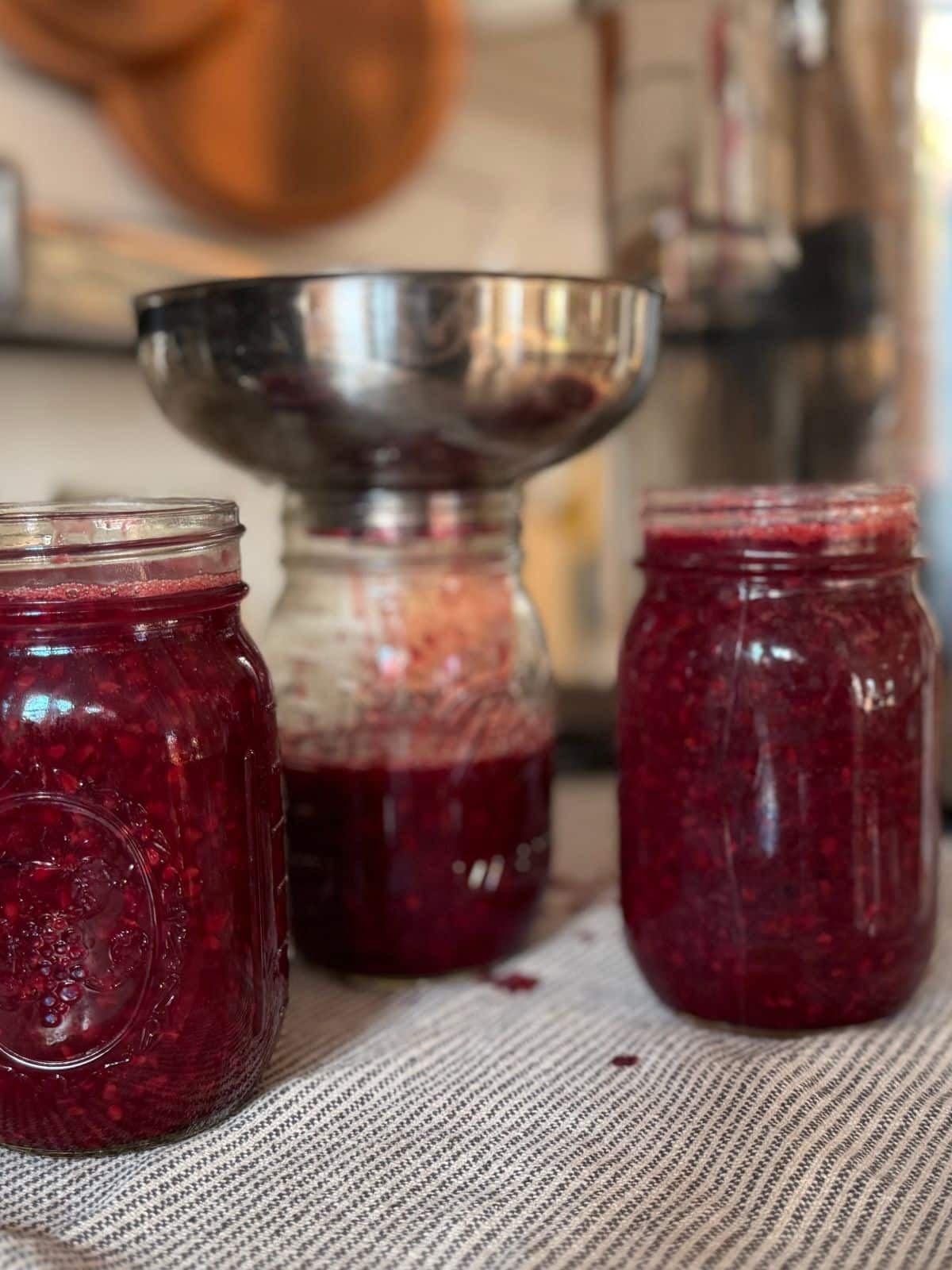 ladeling hot honey blackberry jam jam in to hot mason canning jars
