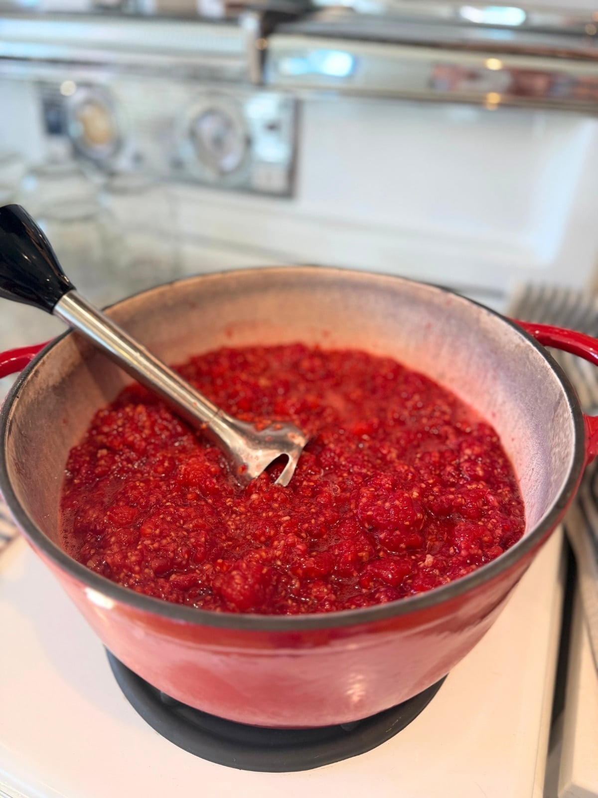 mashed raspberries in pot on the stove with the immersion blender