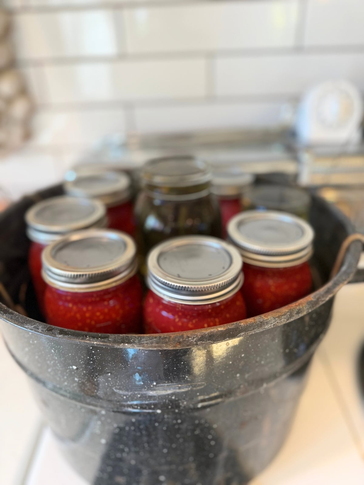pint jars of raspberry jam in water bath canner on stove