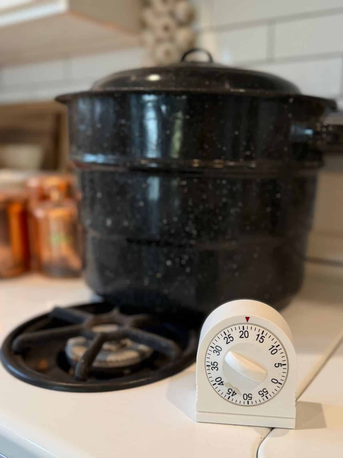an egg timer in froont of canning pot on stove top