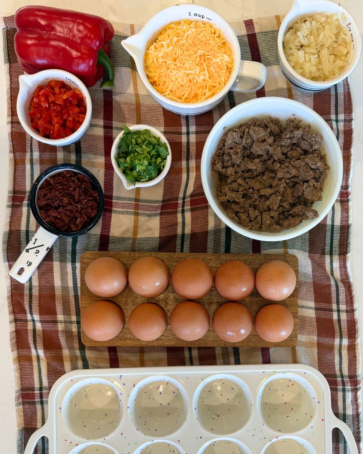 breakfast egg muffin ingredients: minced and sauteed peppers, minuced cilantro, minuced and sauteed onion, cheese, bacon crumbles, cooked turkey sausage, eggs, and silicone muffin baking dish