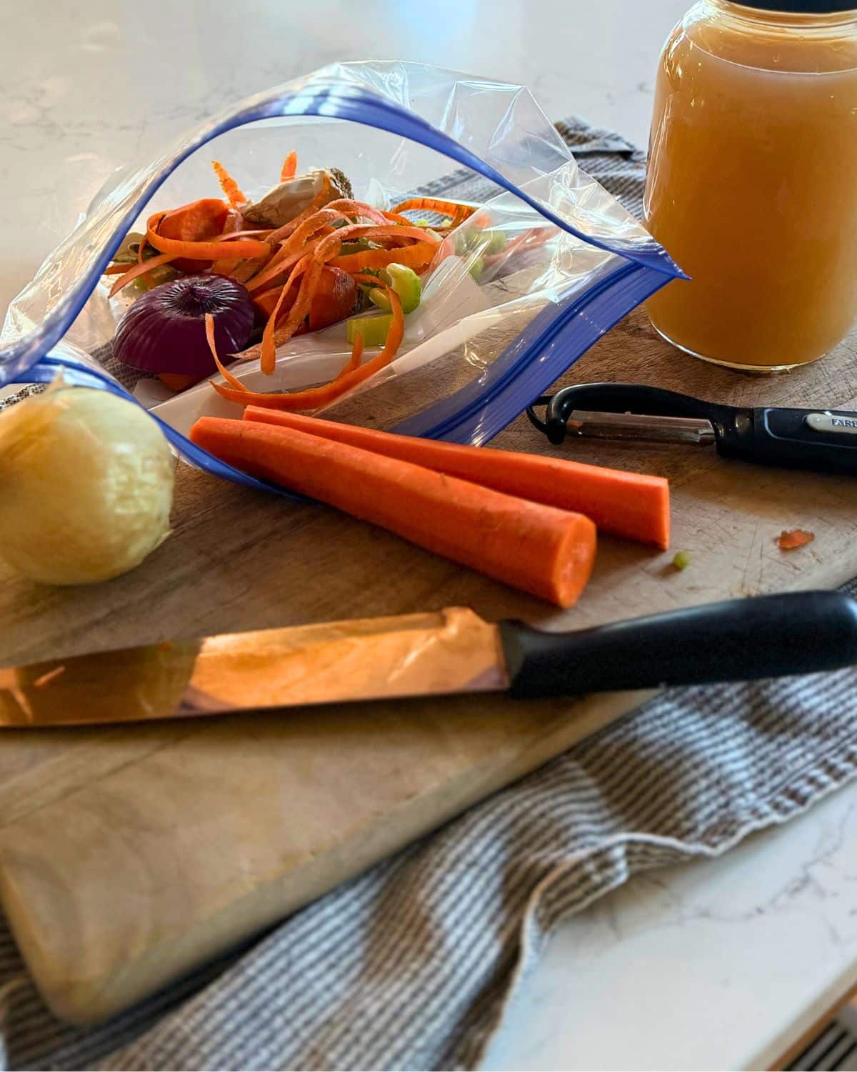 A gallon freezer bag packed with vegetable trimmings sitting on a cutting board next to a jar of homemade broth and fresh vegetables to show depression era kitchen habits for zero waste scrap cooking.