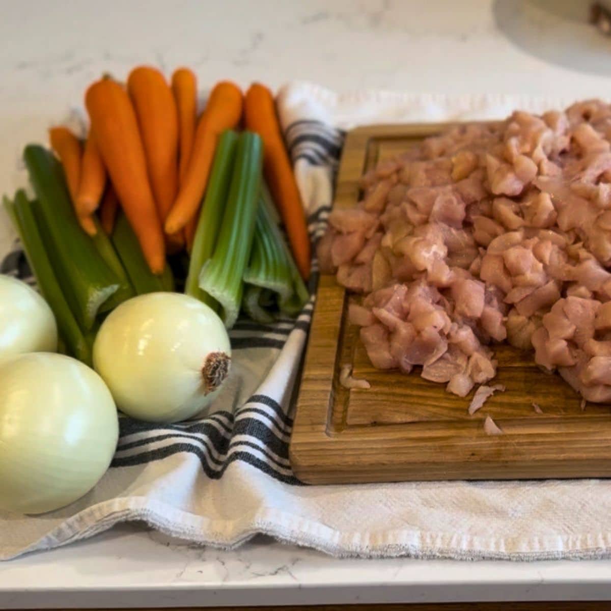 raw pack chicken vegetable soup canning recipe ingredients: raw chopped chicken and carrots, cellery and onions on counter