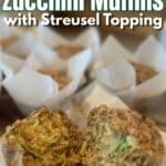 sourdough zucchini muffins cooling on a wood cutting board with one torn open and text