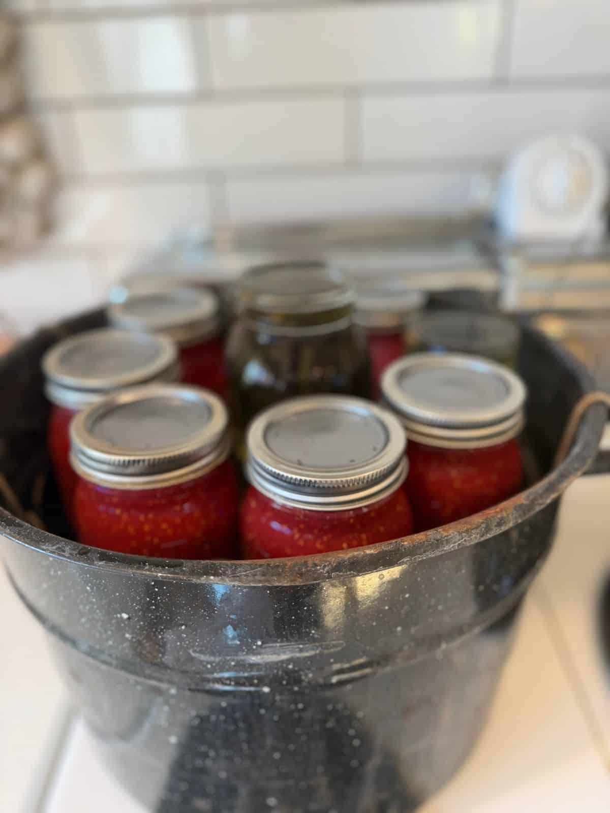 water bath canner with jar rack, jars of jam and an empty jar to fill space