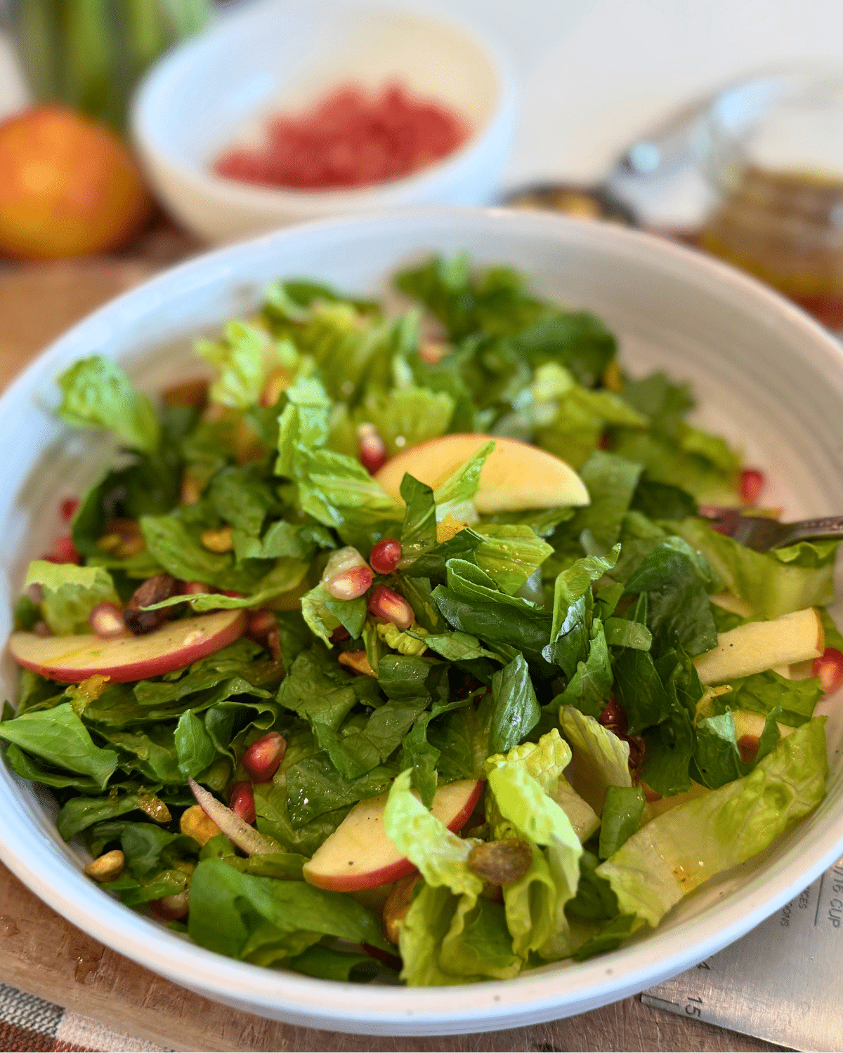 autumn apple salad in white bowl with pomagrante seeds in background