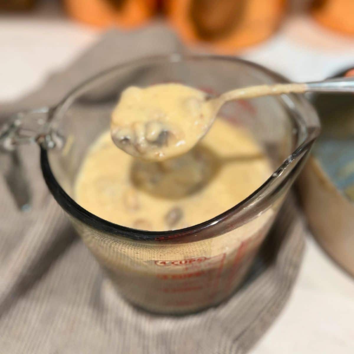 cream of mushroom soup in a large glass measuring bowl with a spoonful up close