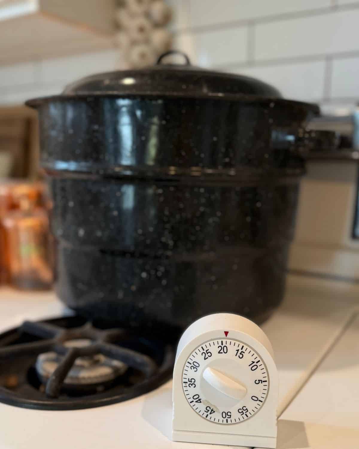 water bath canner with lid on on stove top and timer