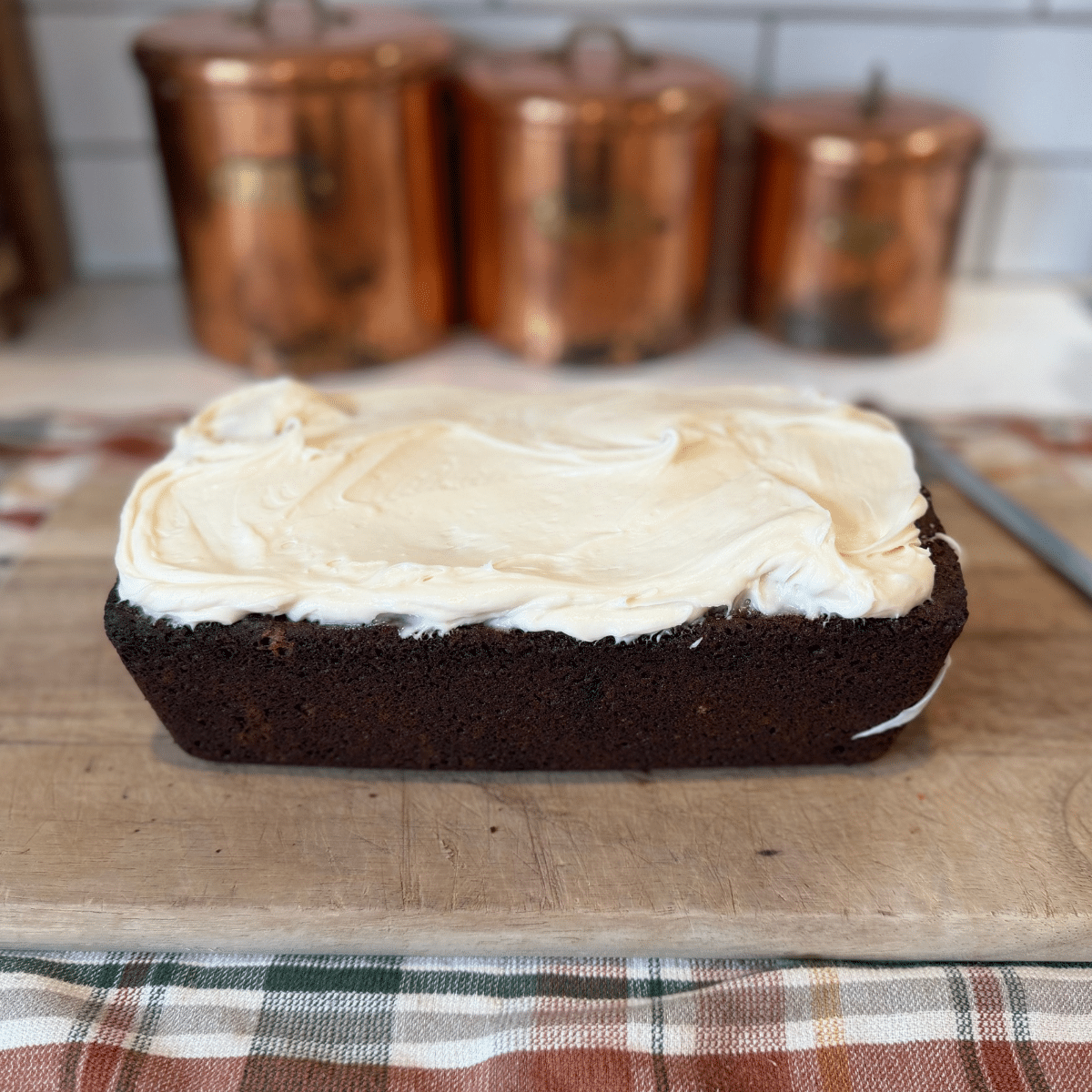 frosted loaf of sourodugh gingerbread before slicing it on a wood cutting board