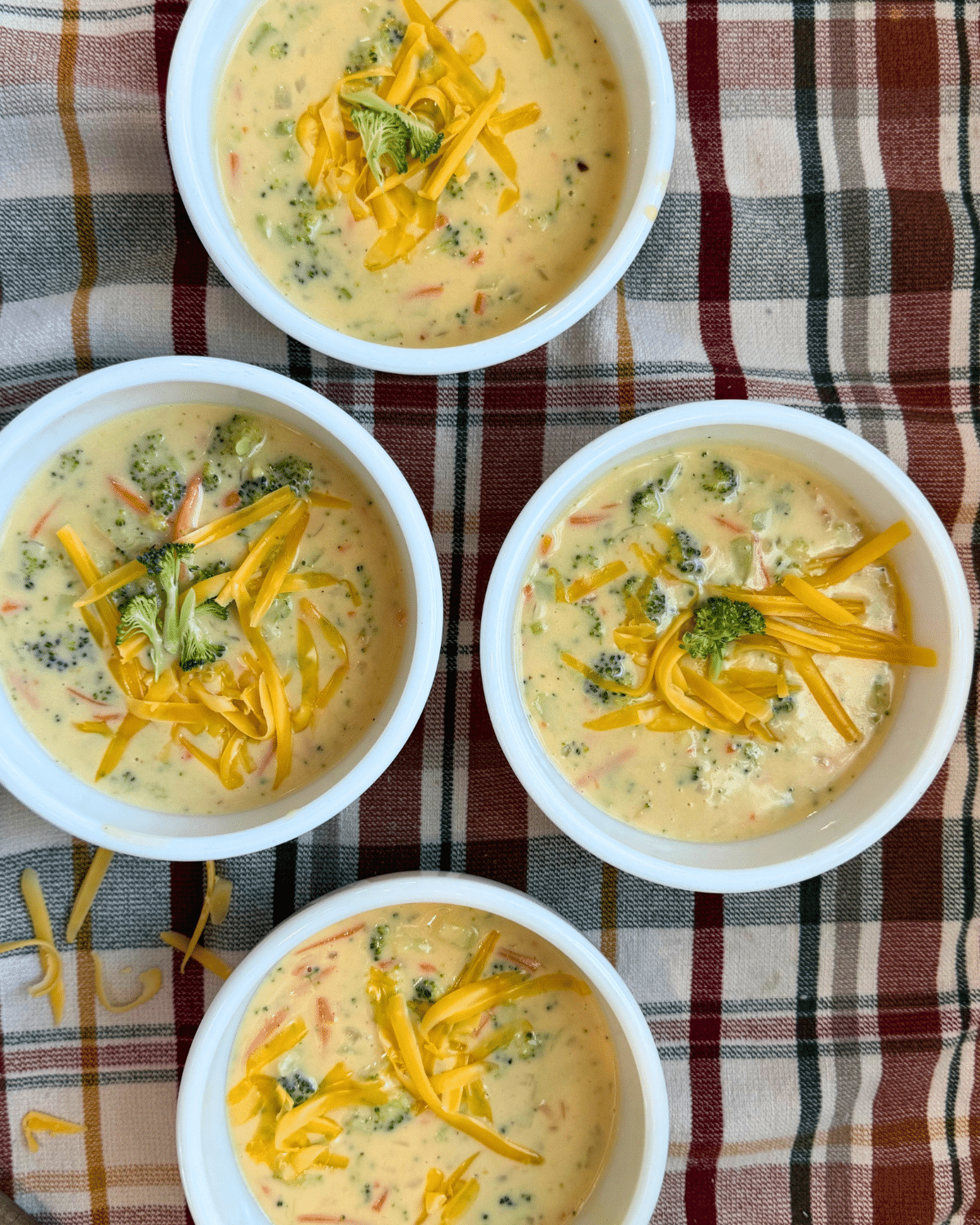 white bowls of this broccoli cheddar soup recipe garnished and ready to serve